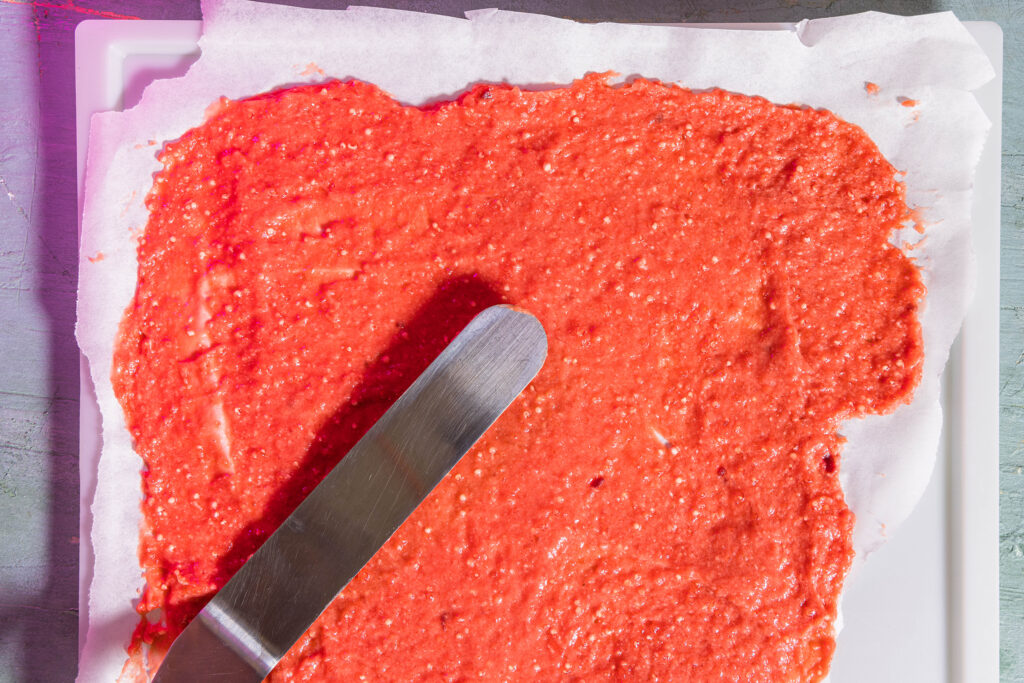 Die rohe Crackermasse wird auf Backpapier dünn ausgestrichen.