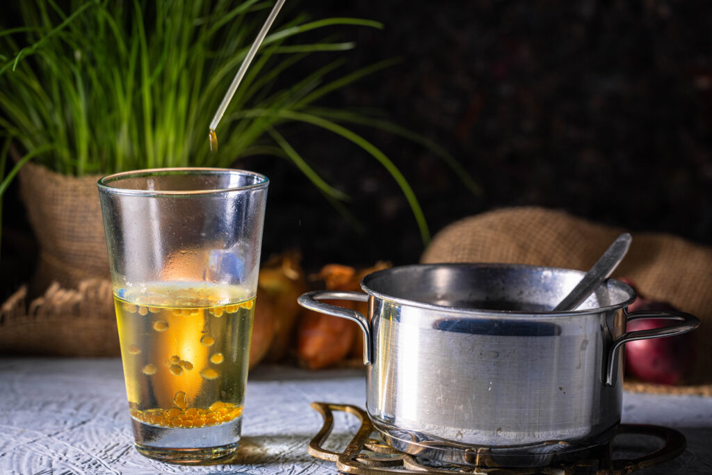 Hheiße Zwiebelbrühe wird mit einer Pipette tropfenweise in ein Glas kaltes Öl geträufelt. Dabei sieht man viele Perlen im Öl hinabsinken.