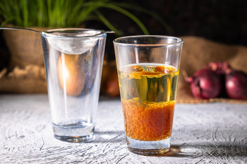 Zwiebelperlen sammeln sich unten in einem Glas Öl.
