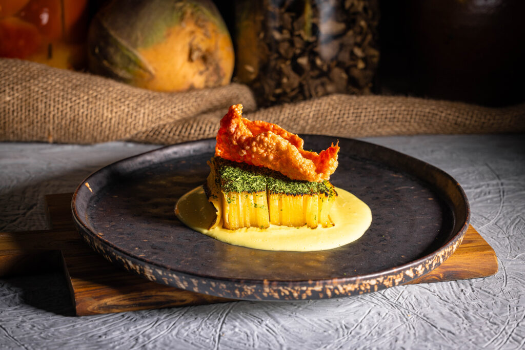 Mille-Feuille, bestreut mit Grünkohlpulver auf die Sauce gesetzt. Anschließend wurde ein gepuffter Rote Beete Cracker darauf platziert.