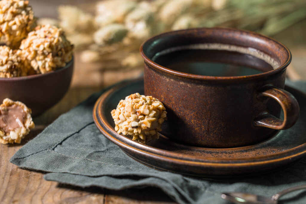 Viotto - vegane Giotto selbst gemacht - in einer Schale. Daneben eine Tasse Kaffe, auf der Untertasse auch ein Giotto. Und ein halbiertes, bei dem man Waffel und Creme sieht davor.