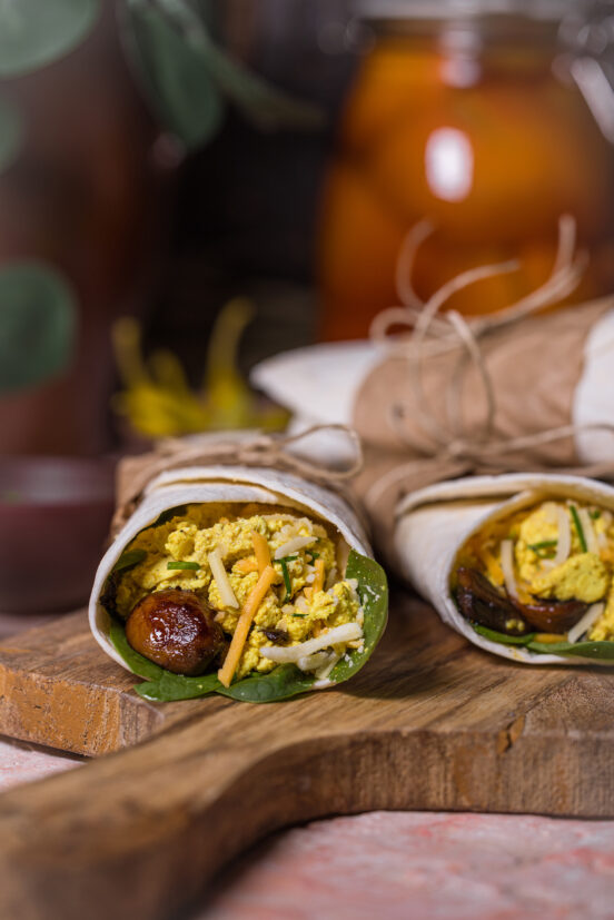 Vegane Egg and Cheese Breakfast Burritos auf einem Holzbrett