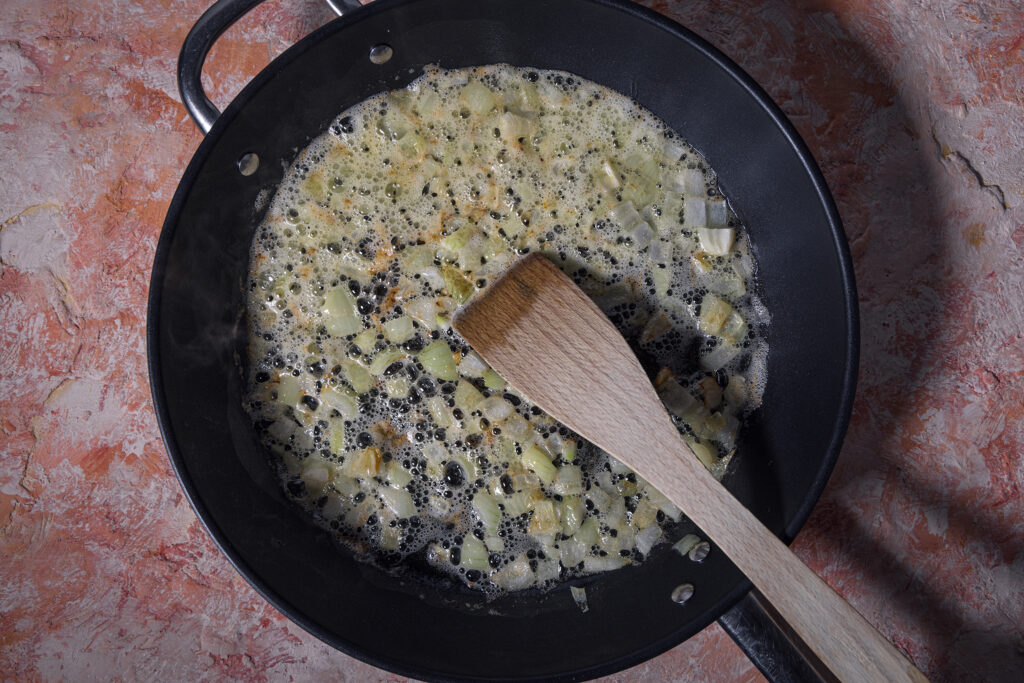 Zwiebelwürfel braten in einer Pfanne an.