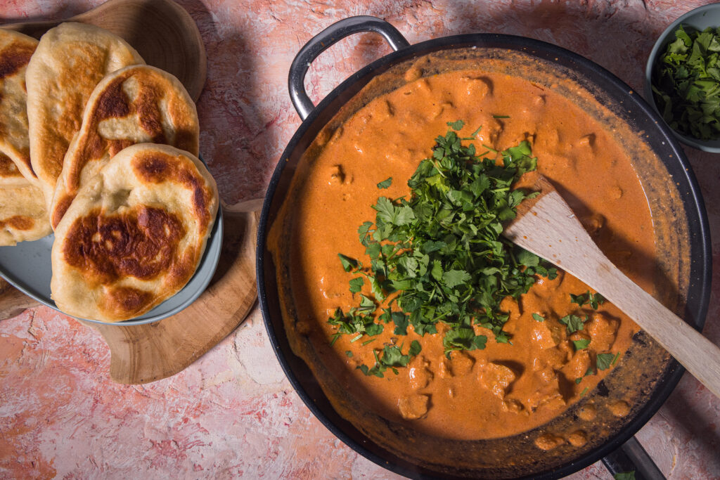 Frischer Koriander wird in eine Pfanne mit Seitan Tikka Masala gegeben.
