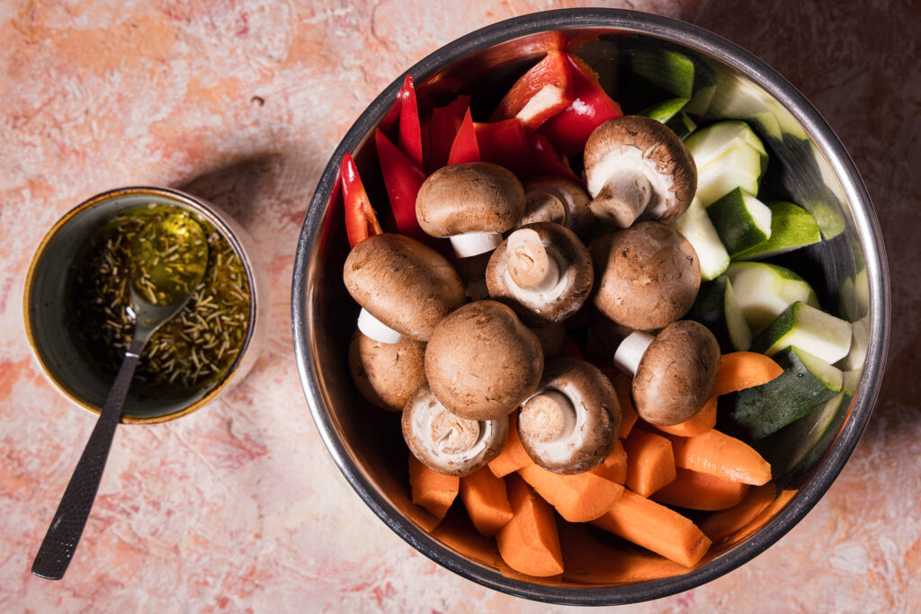 Marinade in einer Schale, daneben eine Schüssel mit geschnittenem Gemüse und Champignons.
