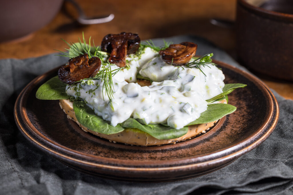 Leek Spread auf einem Bagel mit Kräutern und gebratenen Champignons