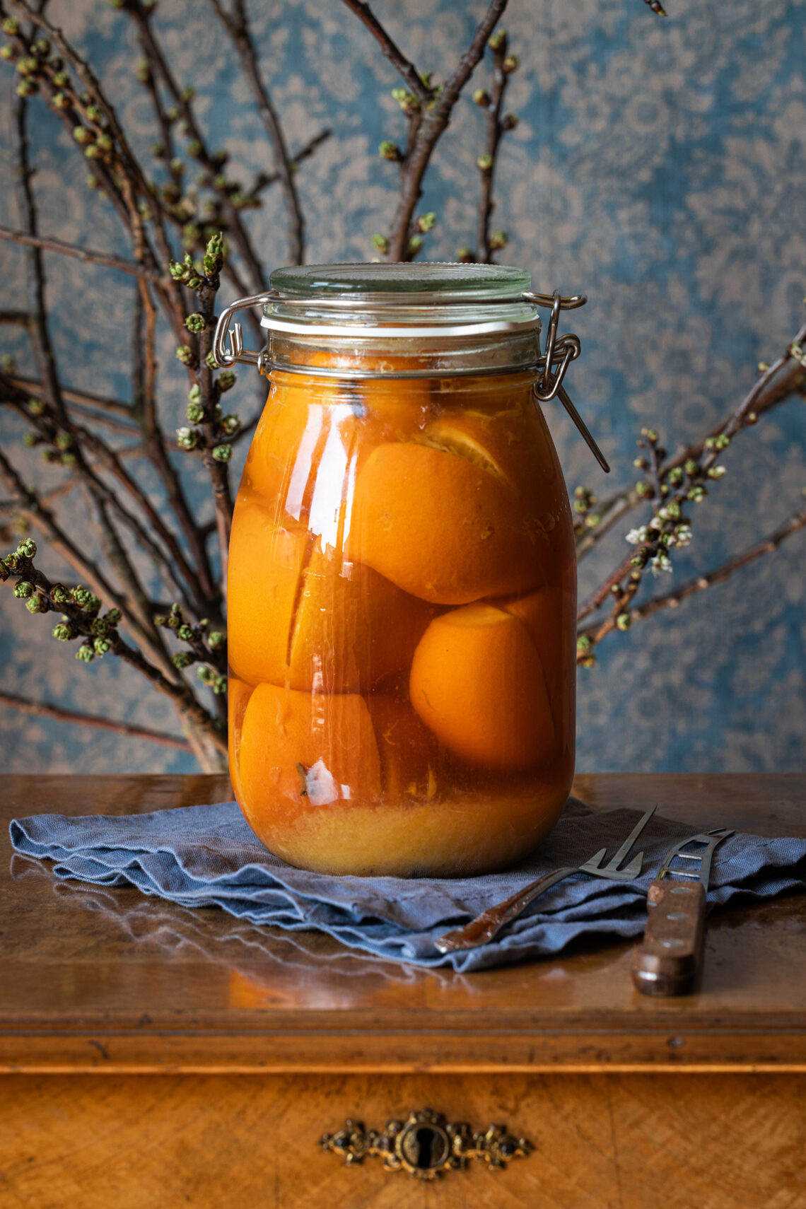 Salzorangen - laktofermentierte, eingelegte Orangen in einem großen Glas auf einem antiken Tisch