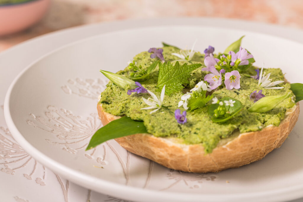 Bärlauchstreich - mit fermentiertem und frischem Bärlauch auf einem Bagel. Garniert mit essbaren Blüten.