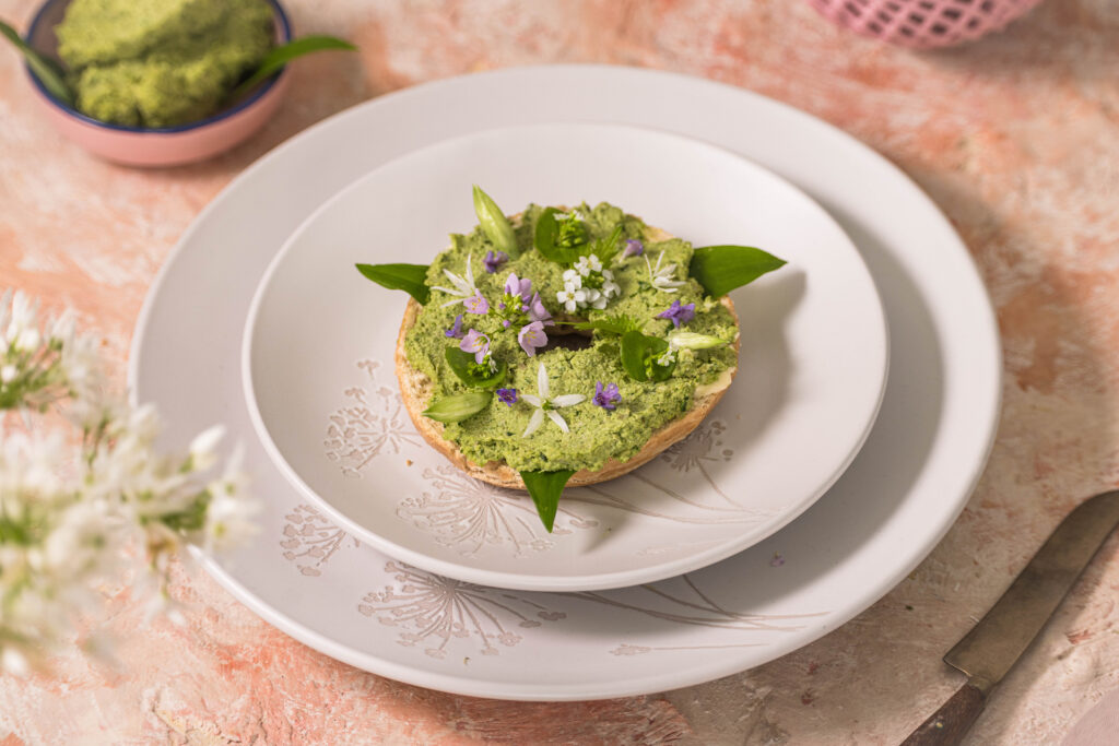 Bärlauchstreich - Brotaufstrich - auf einem Bagel mit essbaren Blüten garniert