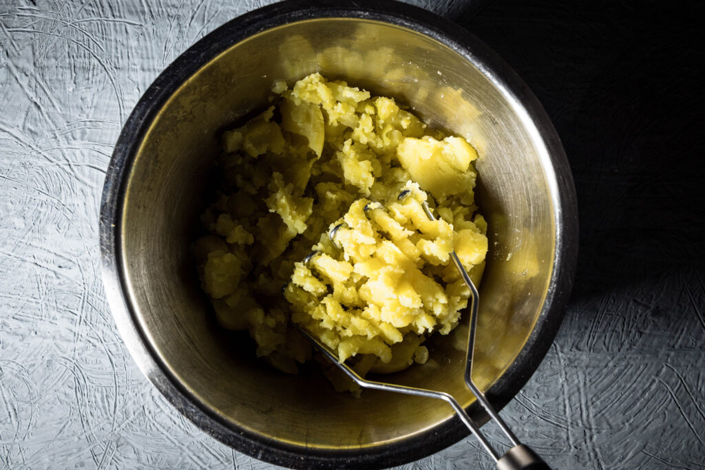 Kartoffeln werden in einer Schüssel gestampft.