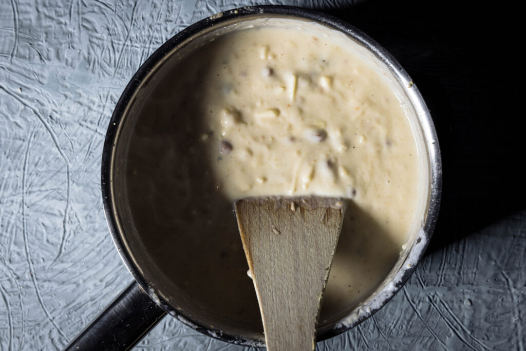 Zubereitung von veganer Käser-Schinken-Sauce, hier werden nach und nach die Zutaten eingerührt.
