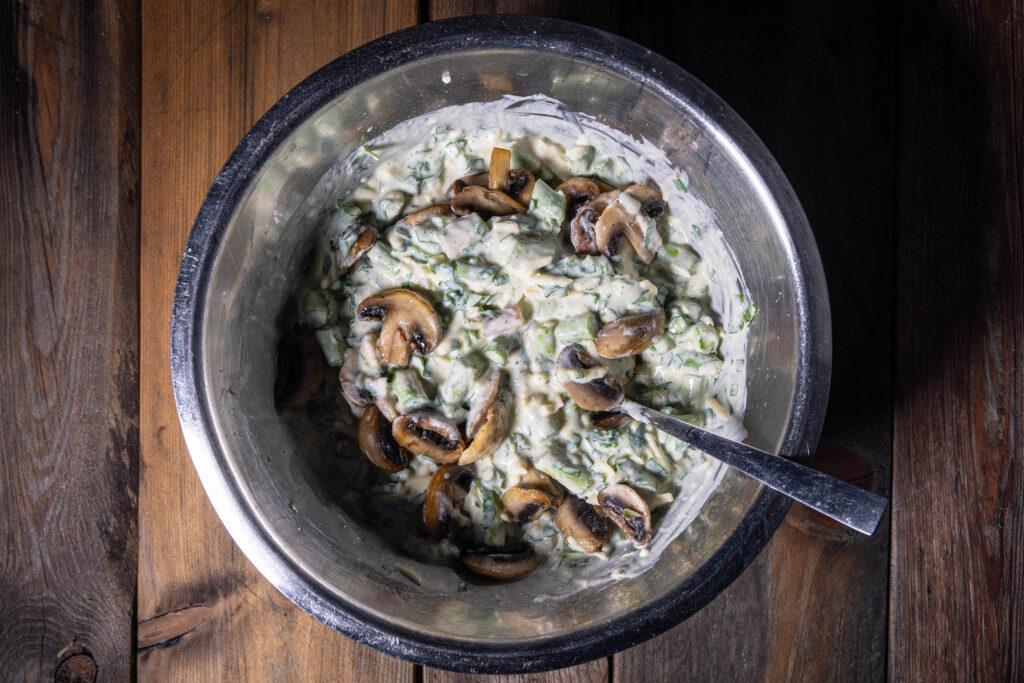 Eine Schüssel mti einer rohen, veganen Quichecreme mit Kräutern, Spargel und gebratenen Champignons.