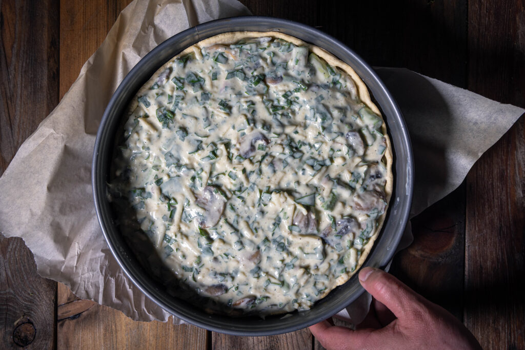 Eine rohe vegane Quiche mit Bärlauch, Spargel und Champignons.