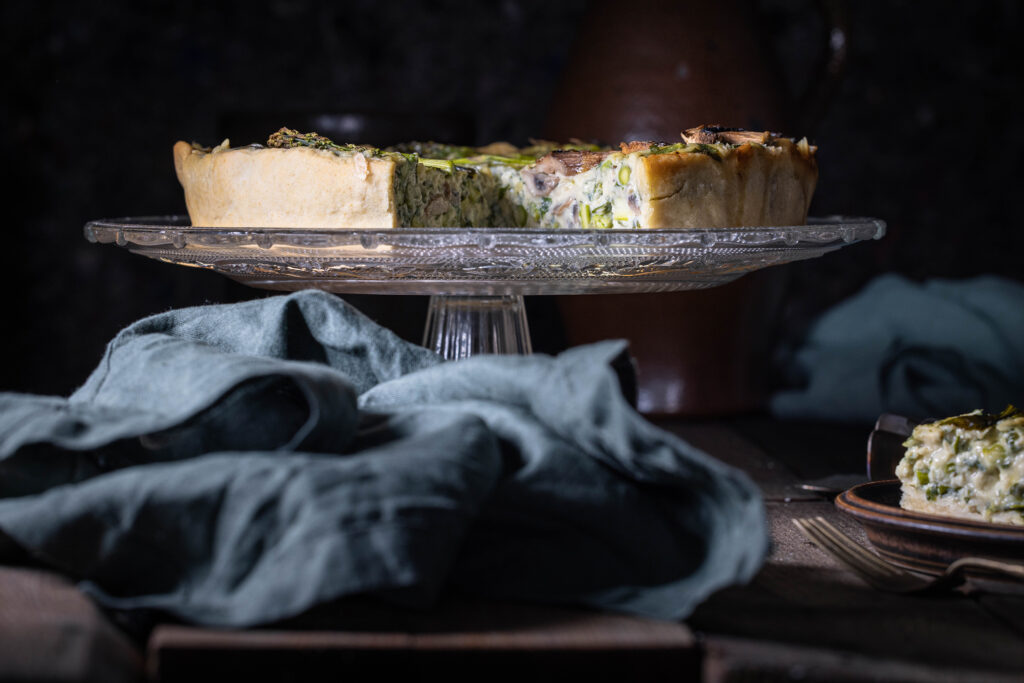 Angeschnittene, vegane Bärlauchquiche auf einem Glasteller