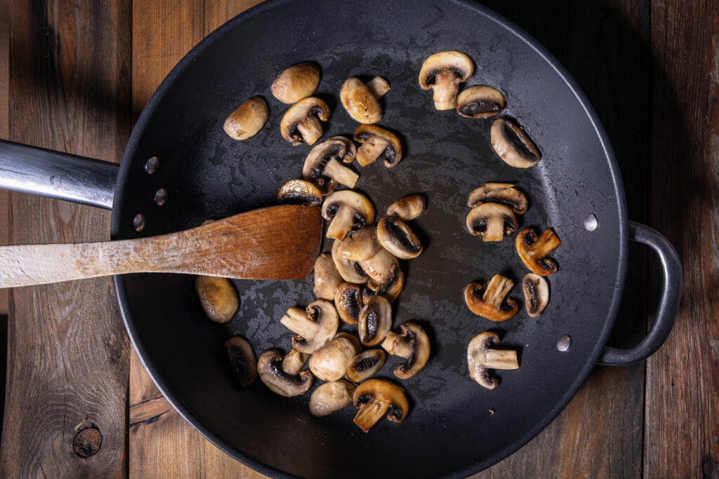 Champignons werden in einer Pfanne angebraten.