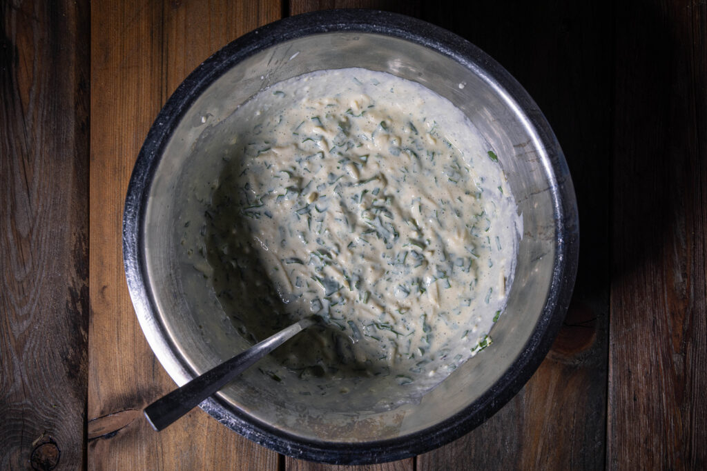 Eine Schüssel mit einer rohen, veganen Quichecreme mit Kräutern.