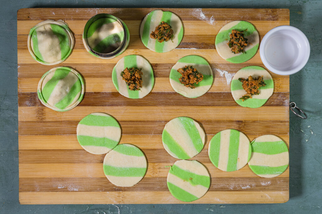 Grün-weiß gestreife Ravioli werden mit einer veganen Bärlauch-HackFüllung gefültlt und zusammengedrückt.