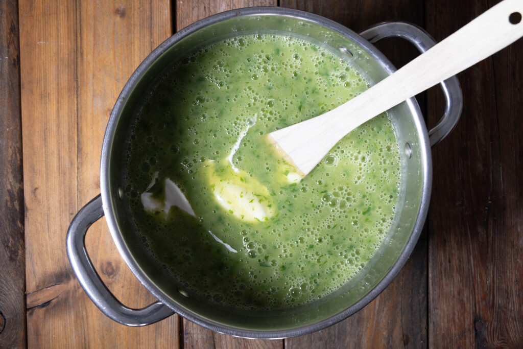In eine cremige Bärlauch-Kartoffel-Suppe wird vegane Creme Fraiche gerührt.