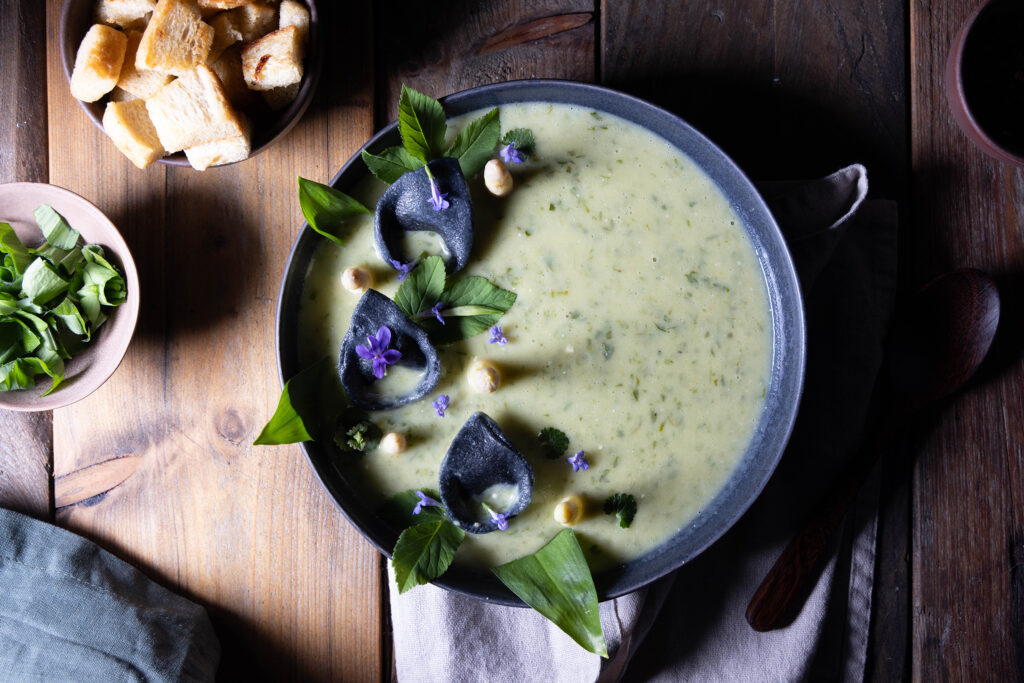 Bärlauch-Kartoffel-Cremesuppe mit Bärlauchtortellini, frischem, weißen Spargel und einer Schale Croutons.