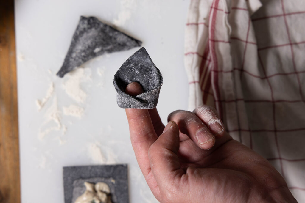 Vegane, schwarze Tortellini werden mit einer Bärlauch-Füllung gefüllt und geformt.