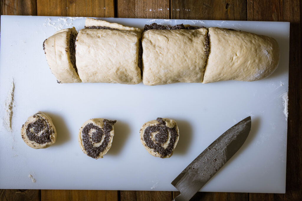 Vegane Mohnschnecken werden aus einer Teigrolle geschnitten.