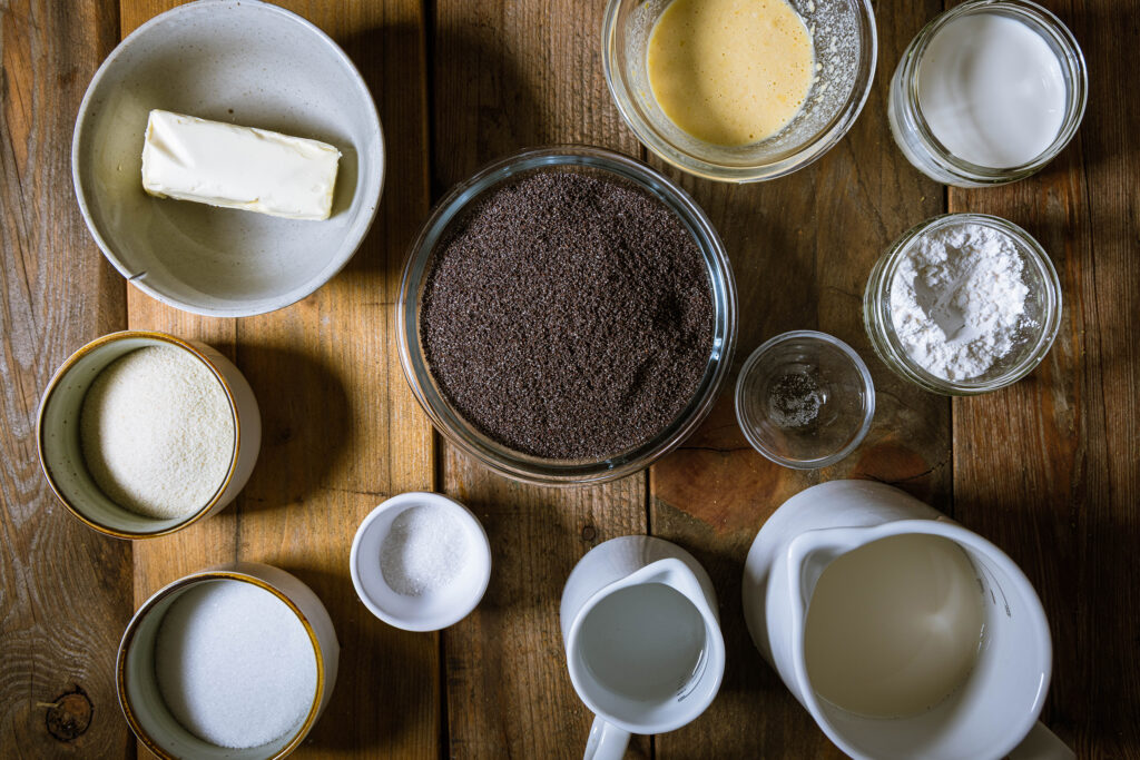 Alle Zutaten für eine saftige, vegane Mohnfüllung auf einem Holztisch.