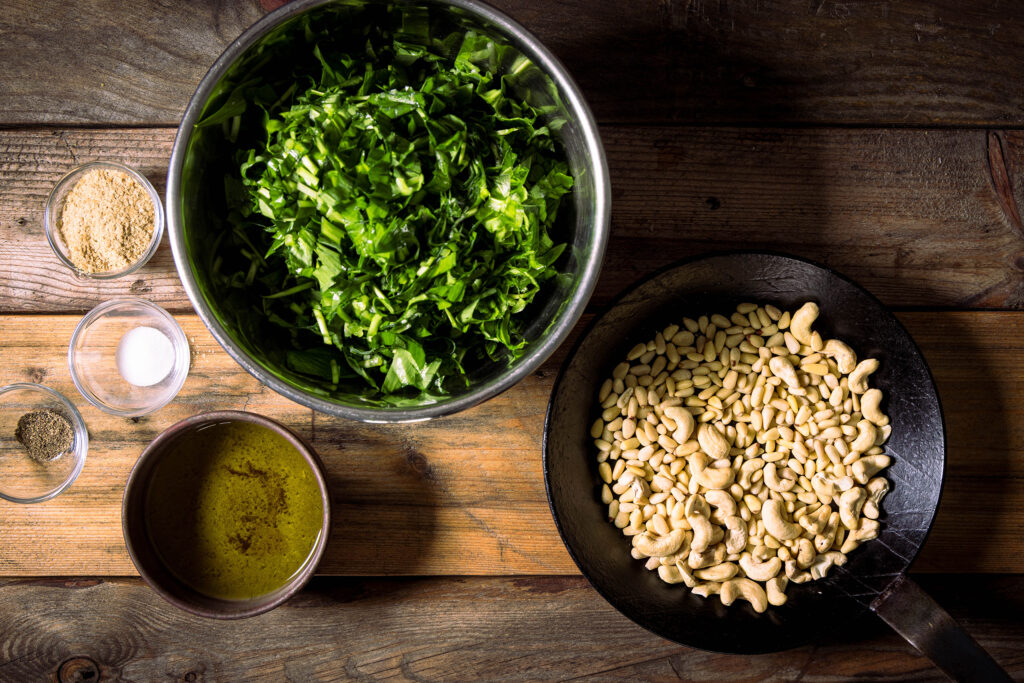 Alle Zutaten für Bärlauchpesto auf einem alten Holztisch.