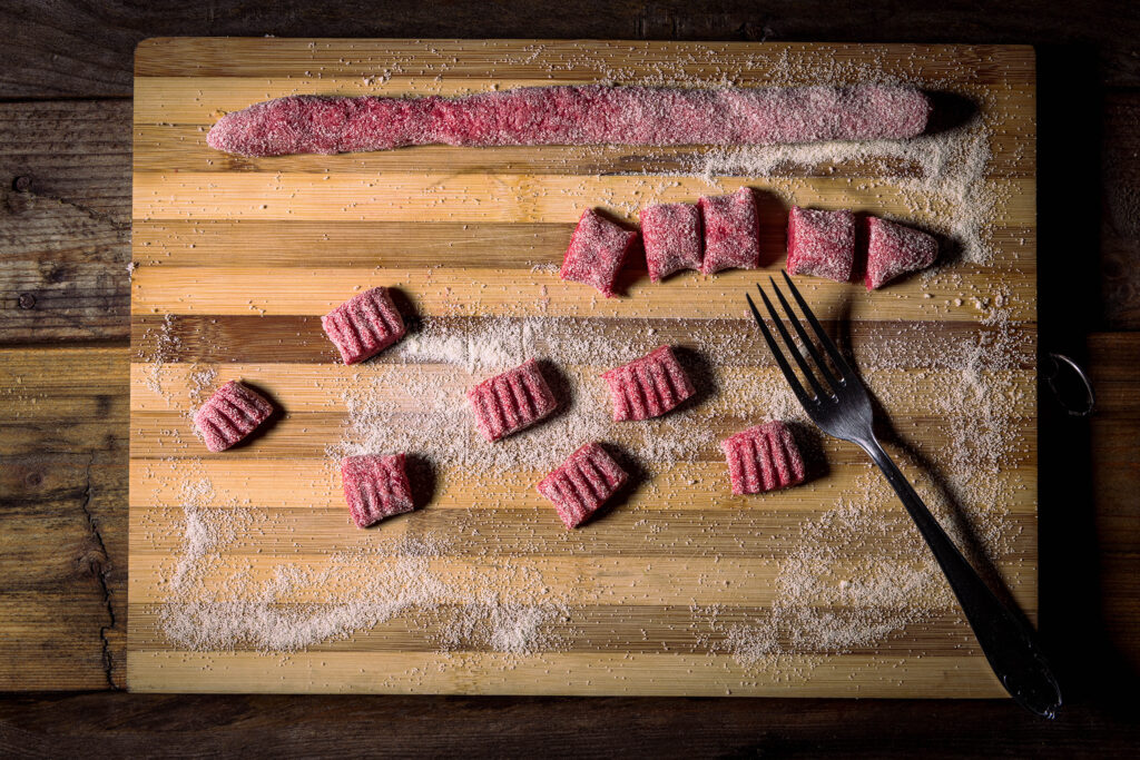 Rote Beete Gnocchi werden auf einem Holzbrett geformt.
