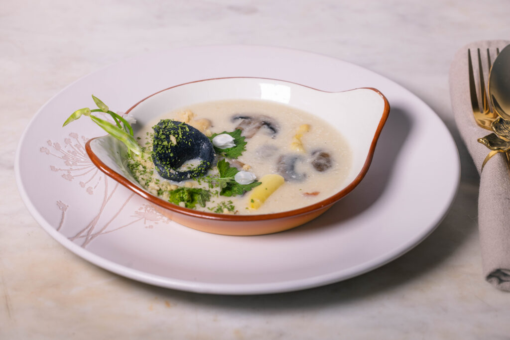 Spargel-Pilz-Cremesuppe – serviert als Vorsuppe mit Bärlauch-Tortellini und frischen Wildkräutern.