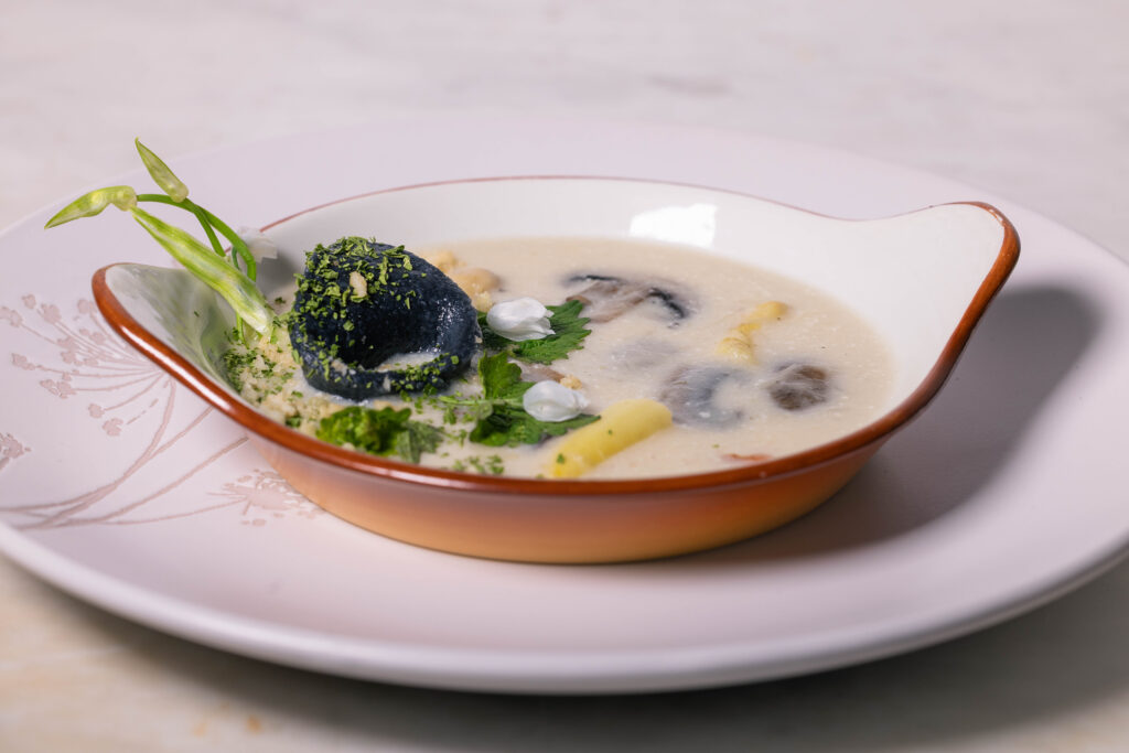 Spargel-Pilz-Cremesuppe – serviert als Vorsuppe mit Bärlauch-Tortellini und frische nWildkräutern.