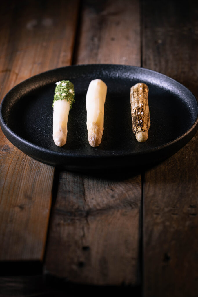 Dreierlei Spargel, schräg von vorne fotografiert auf einem alten Holztisch.