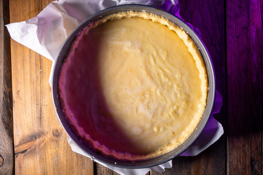 Eine Springform mit Kuchenteig und Vanillepudding.