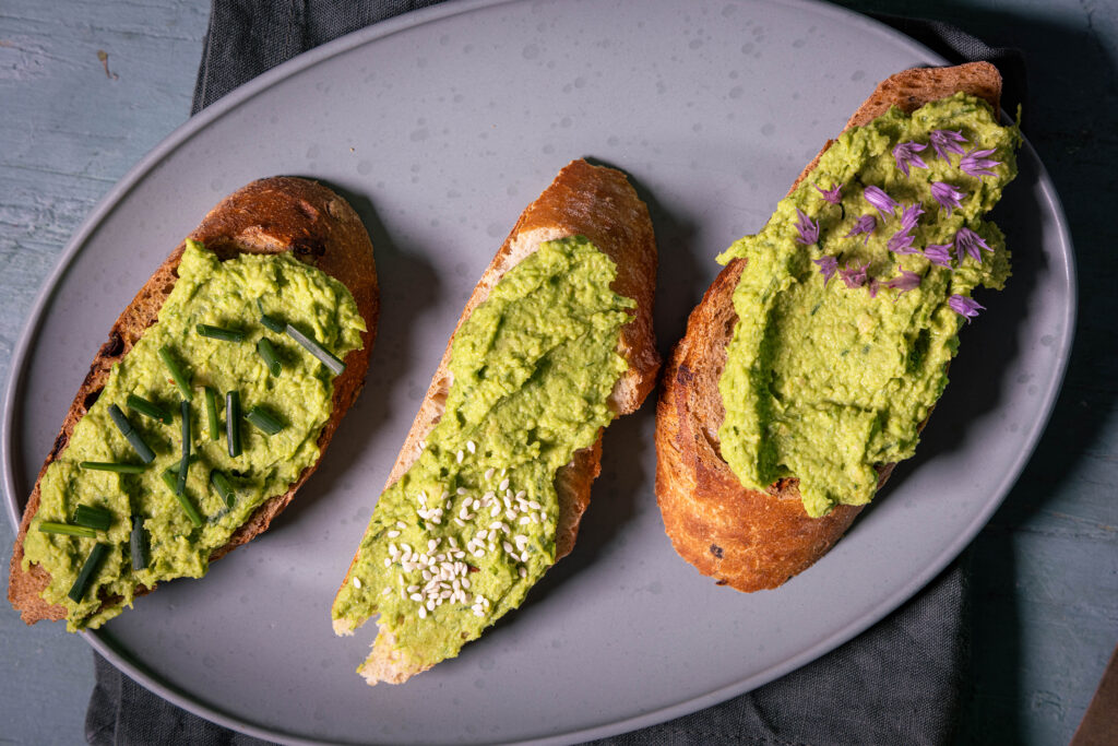 Drei Scheiben Baguette belegt mit Schnittlauch-Hummus