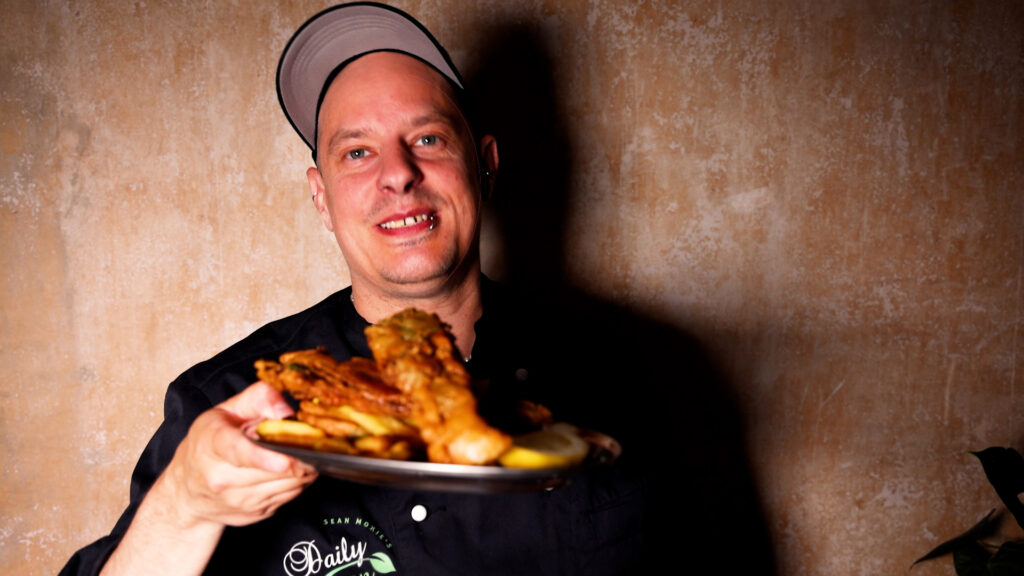 Sean Moxie mit einem Teller Fisch and Chips - der Backfisch ist vegan aus Bananenblüten.