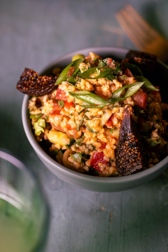 Bulgursalat mit Kefir und getrockneten Feigen in einer grünen Schale
