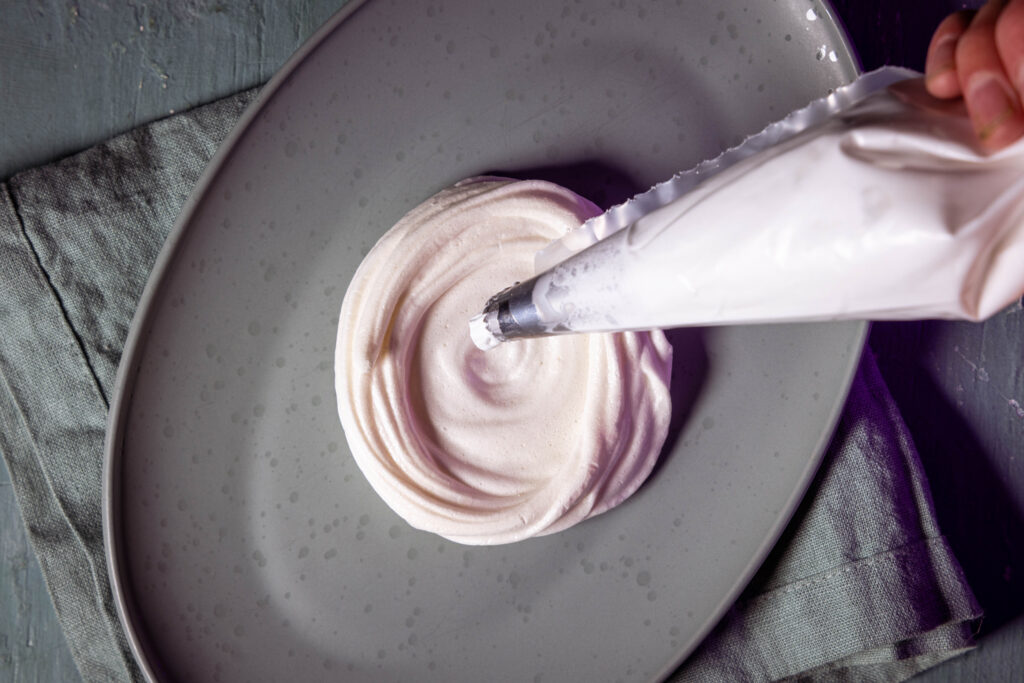 Vegane Baiserschalen werden mit pflanzlicher Schlagsahne für Pavlova gefüllt.