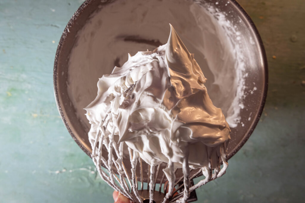 Vegane Baisermasse in einer Schüssel und an einem Schneebesen.