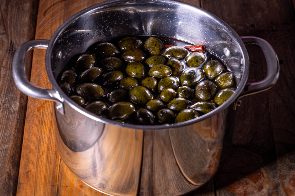 Unreifen Walnüsse werden zum kochenden Sirup dazu gegeben und darin eingekocht.