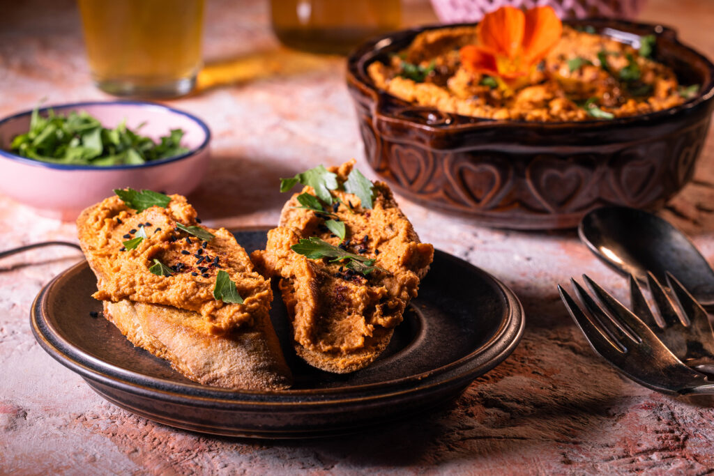 Selbstgemachter Hummus mit Tomaten. Auf Brot und in einer Schale.
