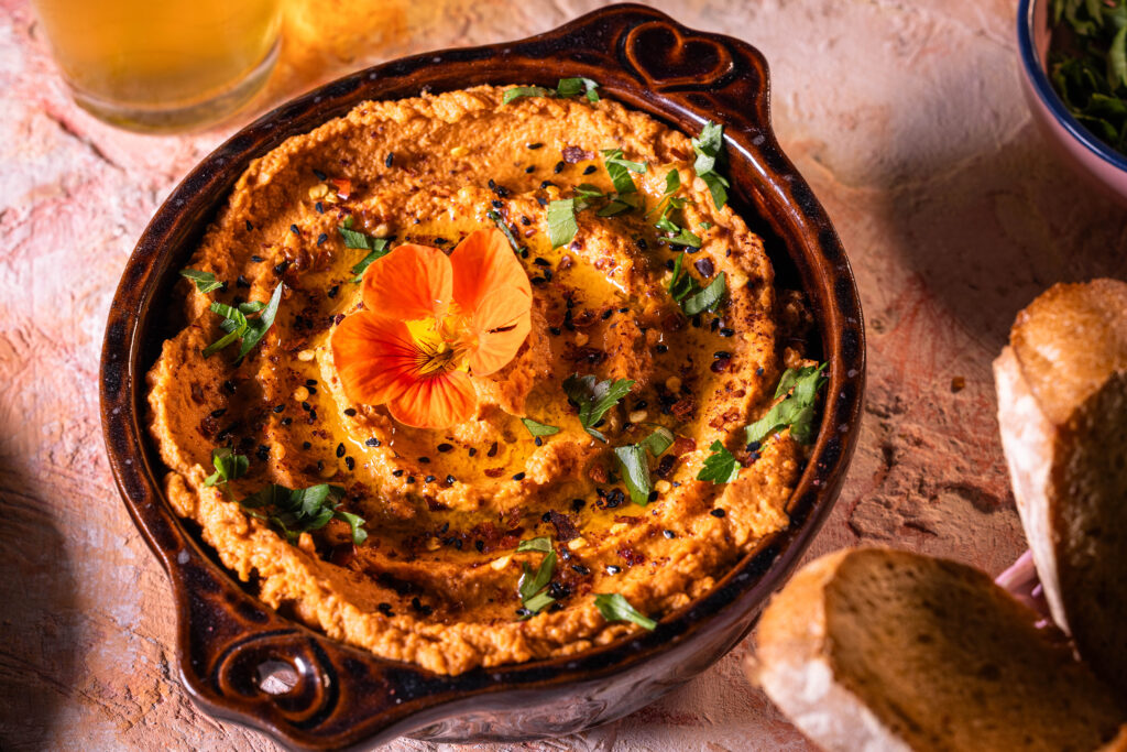 Tomaten-Hummus mit Kräutern und Gewürzen in einer Schale.