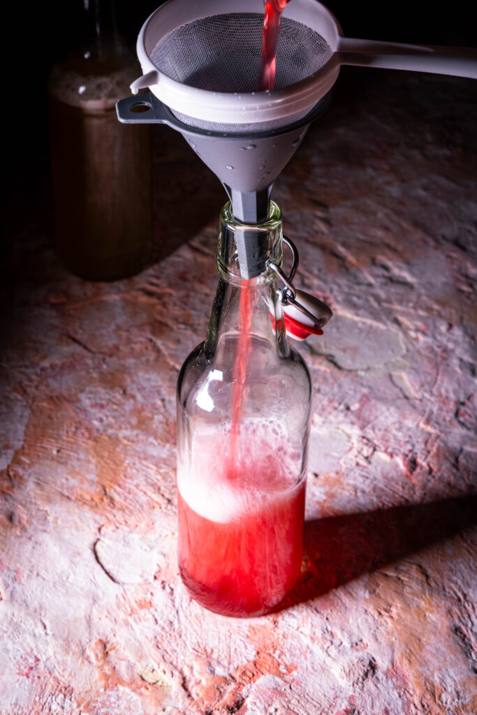 Kombucha wird nch der Zweitfermentation in eine Flasche abgeseiht.