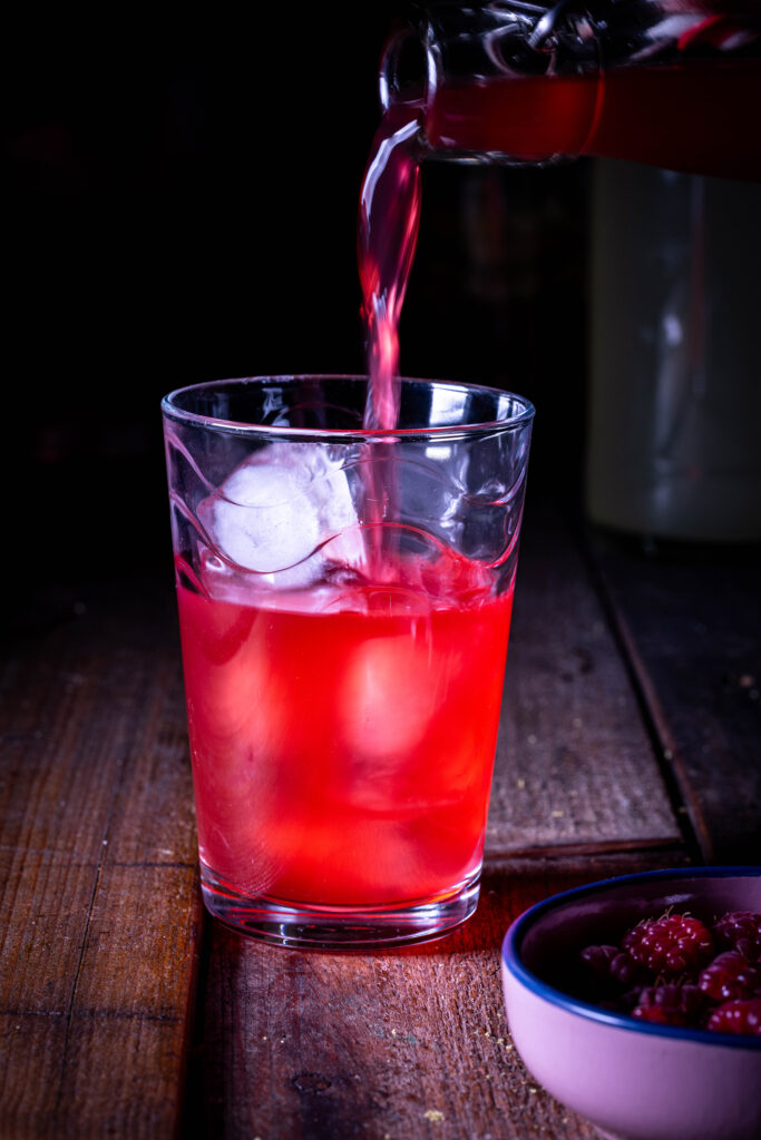 HImbeerkefir wird in ein Glas mit Eiswürfeln geschenkt.
