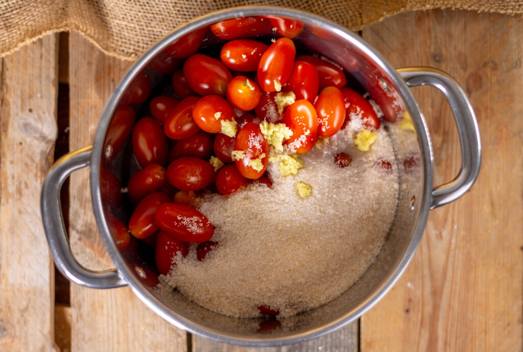 Alle Zutaten für die Konfitüre aus Tomaten in einem Kochtopf.