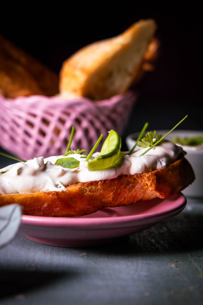 Vrischkäse - veganer Frischkäse mit Kräutern auf einem Stück Brot.