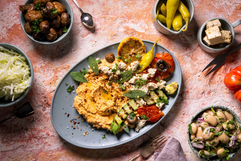 Veganer Scharfer Schafskäse Dip - Hot Sheperd - mit verschiedenen Beilagen auf einem Teller angerichtet.