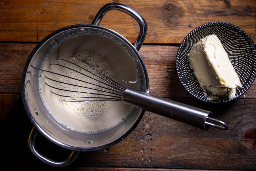 Ein Kochtopf mit einem Sojamilchgemisch für Pudding udn eine Schale vegane Butter.
