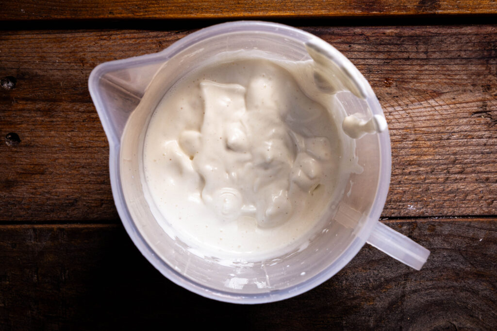 Vegane Mayonnaise aus Aquafaba, frisch zubereitet, in einem Messbecher.