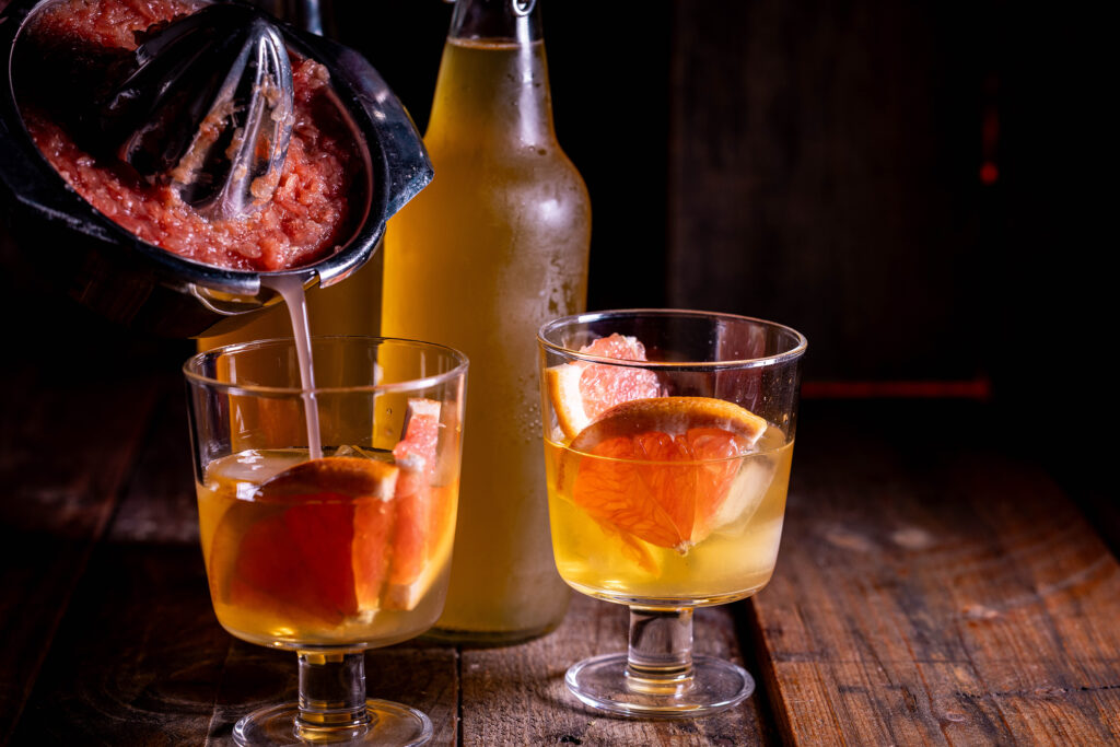 Grapefruitsaft wird aus einer Saftpresse in Gläser gegossen.