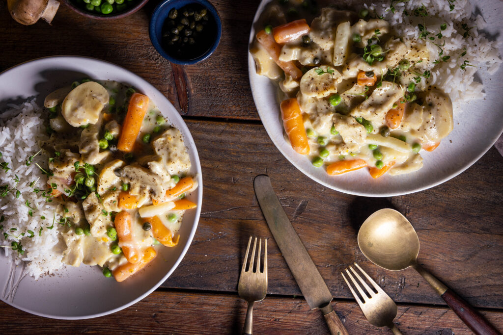Veganes Hühnerfrikassee auf zwei Tellern mit Reis.