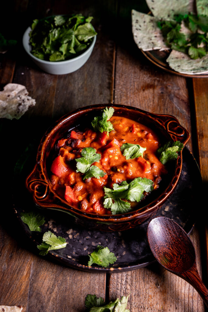 Kreolisches Schwarze-Bohnen-Chili in einer Schale, mit Koriander darauf.